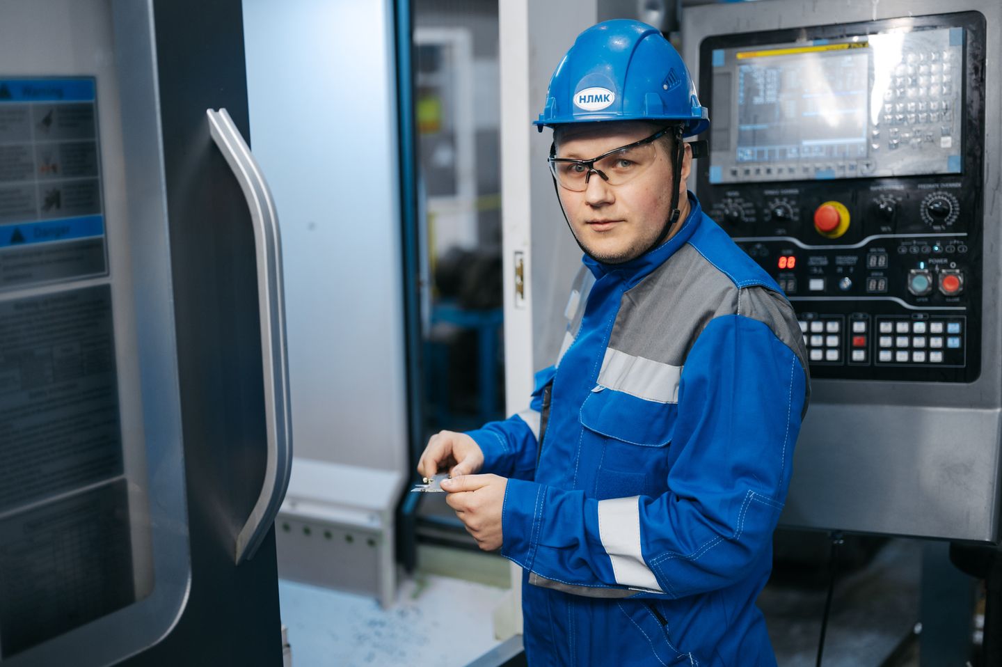 Industrial engineer operating a CNC machine on a factory floor.