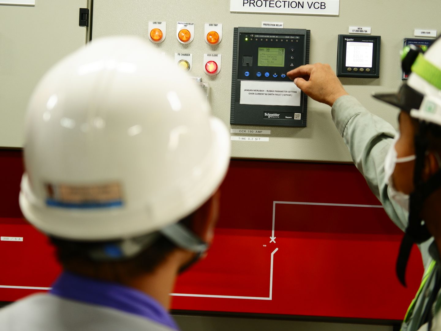 Engineers operating an industrial control panel in a production facility.