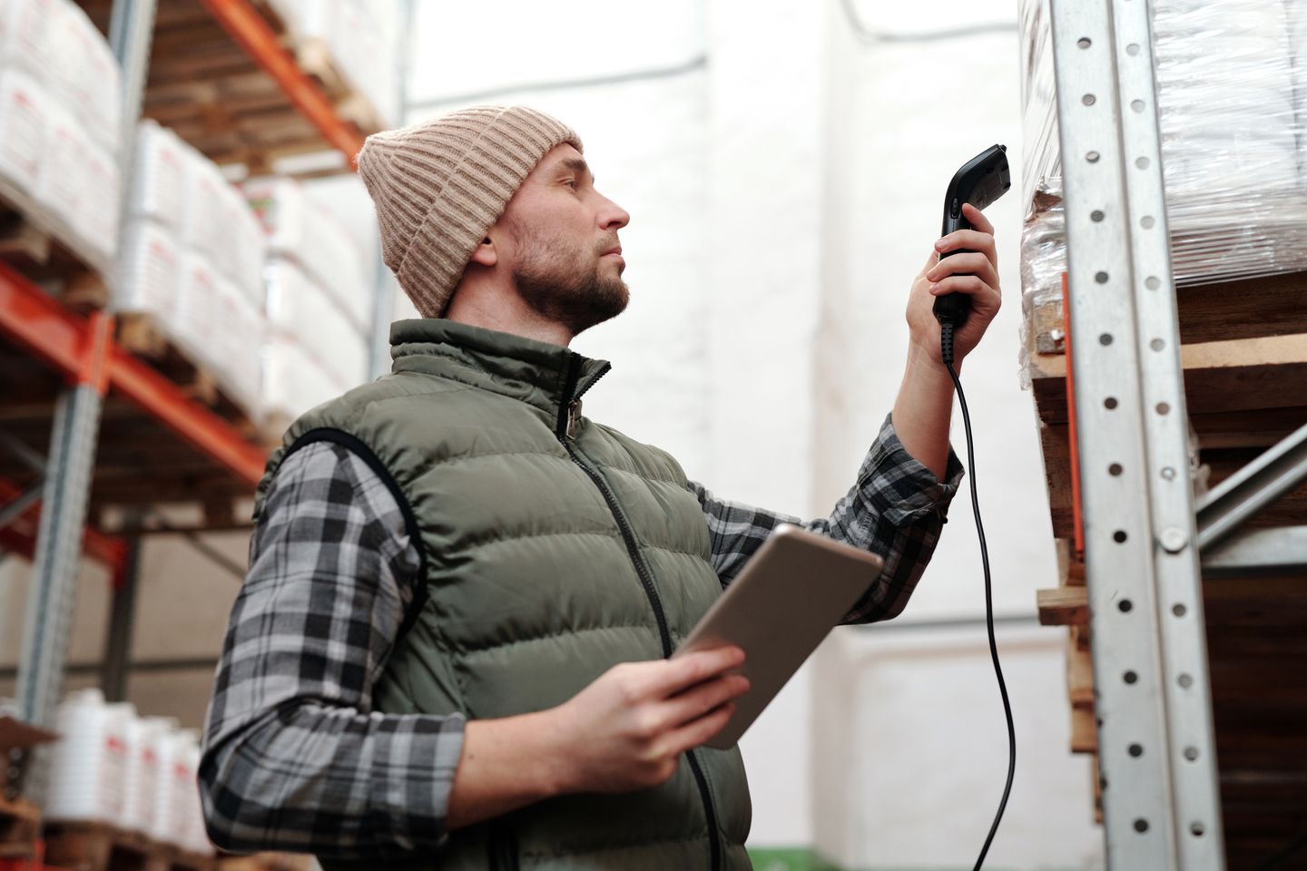 Warehouse worker scanning stock with a handheld device and tablet.