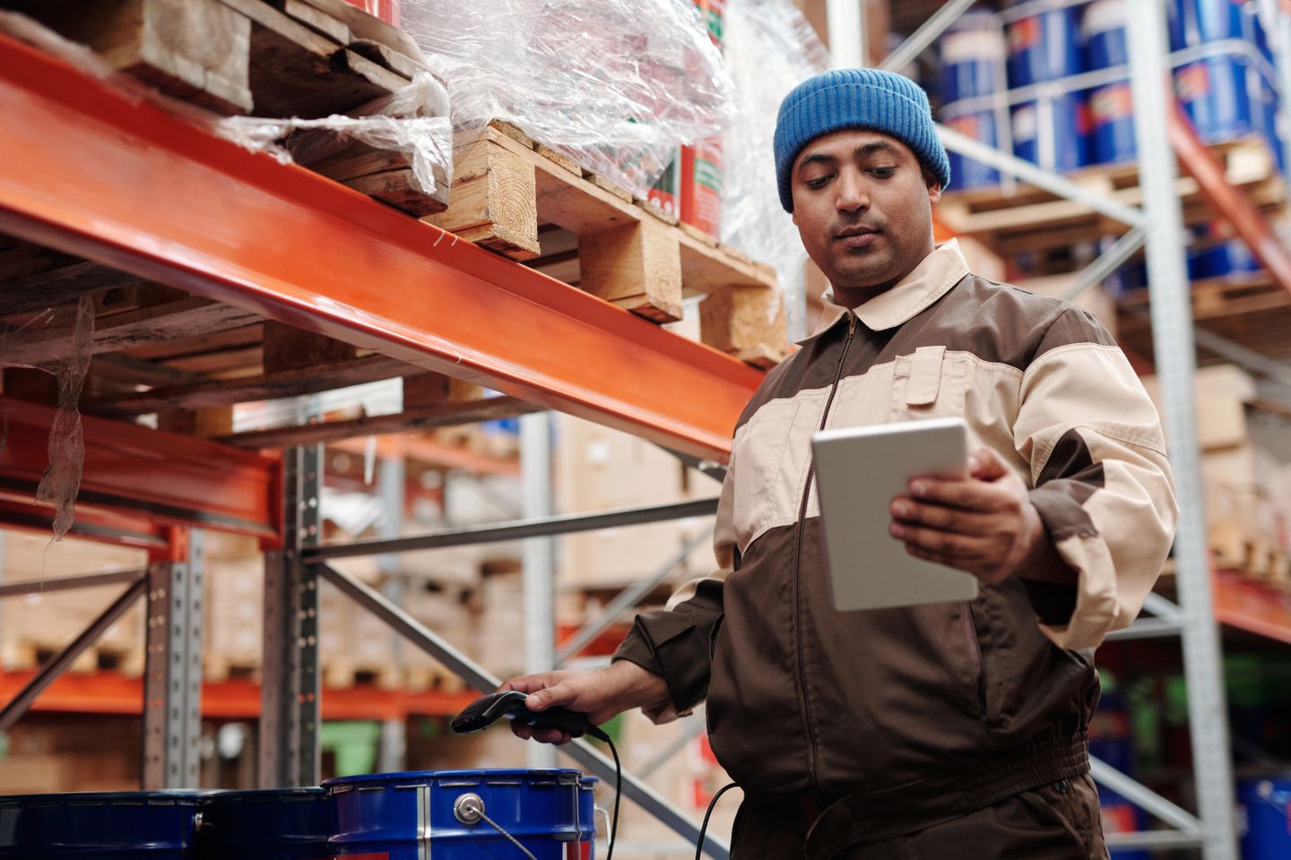 Warehouse employee reviewing inventory on a handheld tablet.