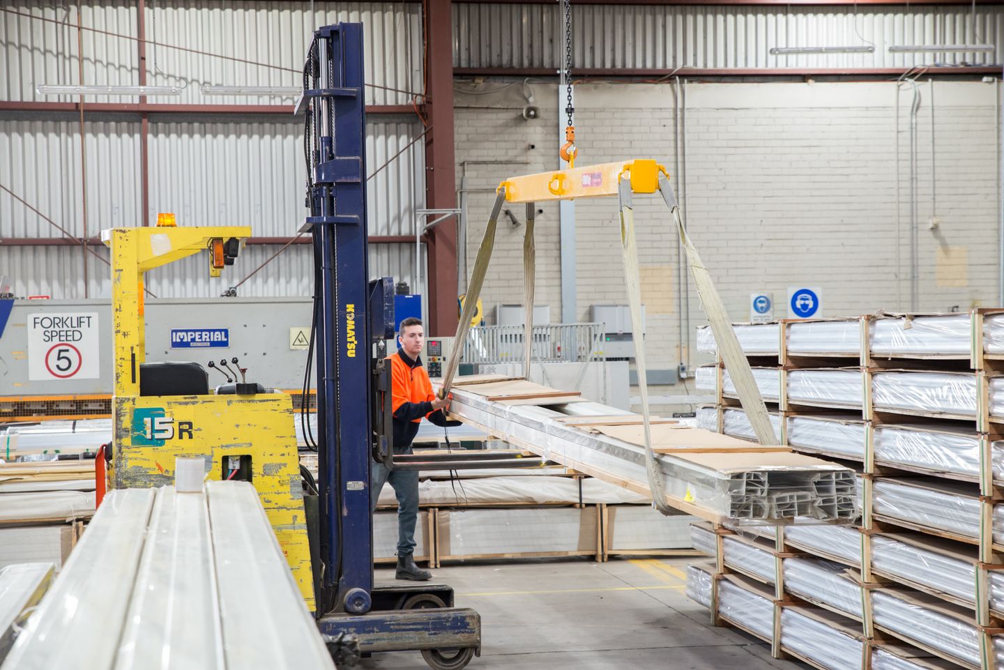 Forklift operator moving material through an industrial warehouse.